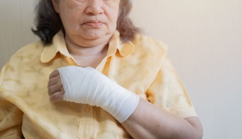 Old Asian woman with gauze bandage wrapped around her injured hand. - resident on resident assault concept