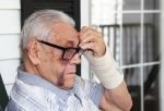 A senior man with facial injuries and a splint on his wrist - nursing home resident assault concept