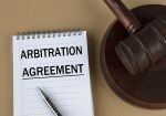 ARBITRATION AGREEMENT - words in white notebook on the background of the judge's hammer with stand