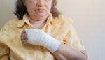 Old Asian woman with gauze bandage wrapped around her injured hand. - resident on resident assault concept